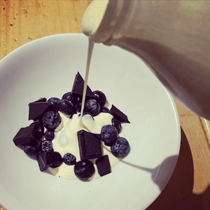 Picture of Cream being poured of blueberries and dark chocolate.